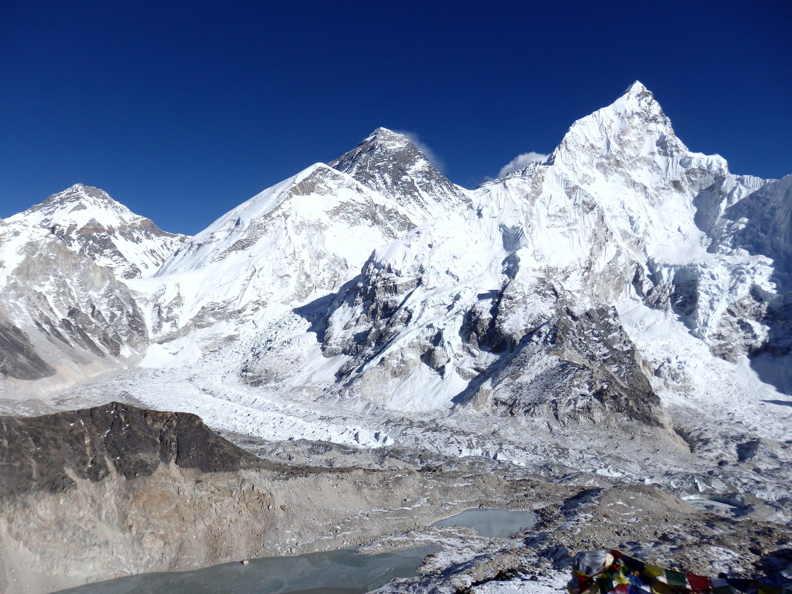 "Trekkers hiking on the trail to Everest Base Camp with stunning views of the Himalayas in the background."